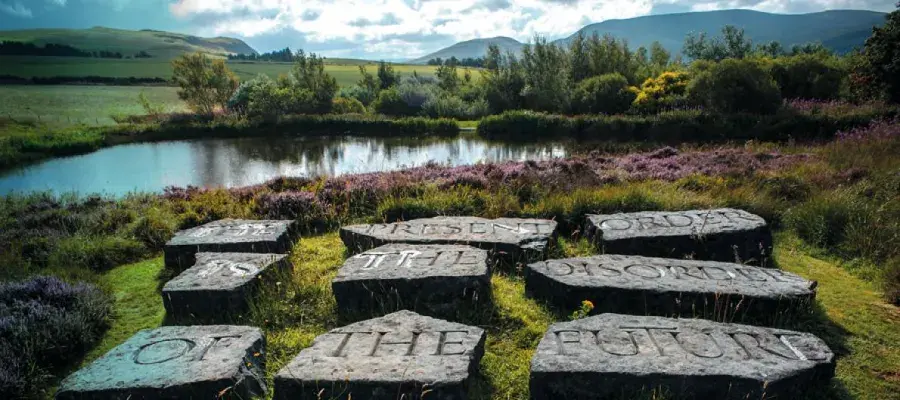 Set of stones with carved text, with lake and hills in the background