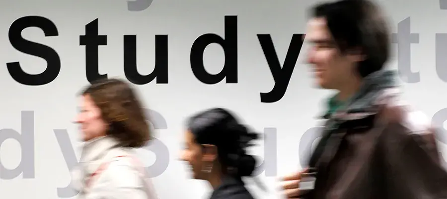 Students walk in front of a wall that has 'study' printed on it.