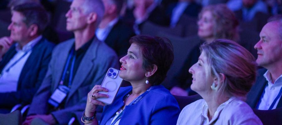 A crowd listens to a speech at a tech conference event.