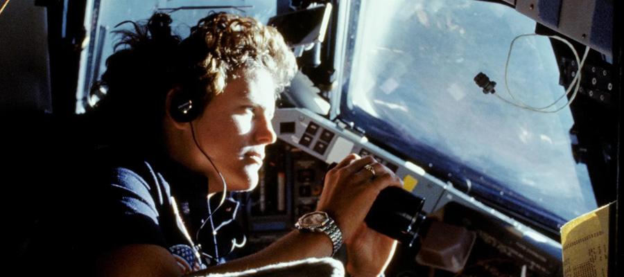 Astronaut Kathy Sullivan uses a pair of binoculars to do some magnified viewing through the forward cabin windows of the Earth-orbiting space shuttle Challenger in 1984. 