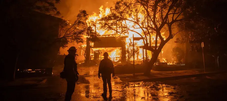 LOS ANGELES, CALIFORNIA - JANUARY 8: Firefighters watch the flames from the Palisades Fire burning a home during a powerful windstorm on January 8, 2025 in the Pacific Palisades neighborhood of Los Angeles, California. The fast-moving wildfire is threatening homes in the coastal neighborhood amid intense Santa Ana Winds and dry conditions in Southern California. (Photo by Apu Gomes/Getty Images)