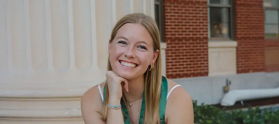 Lydia smiling to camera sitting outside a building