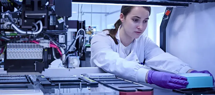 Woman organises experiment in pipetting machine. Engineering biology