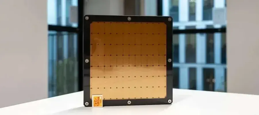 Large computer chip on a table with a postage stamp in the bottom corner of it for scale.