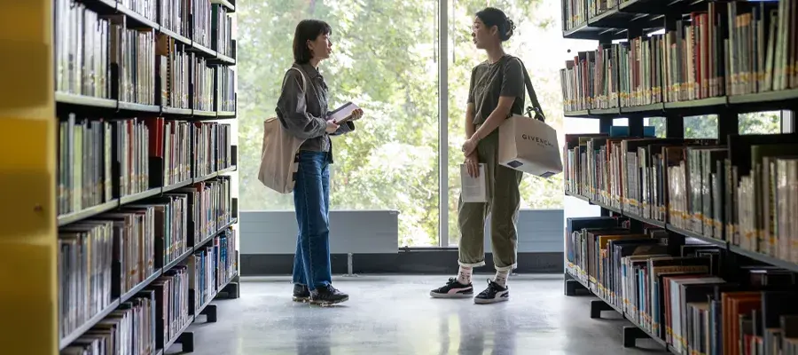 studetns standing in the library, surrounded by books