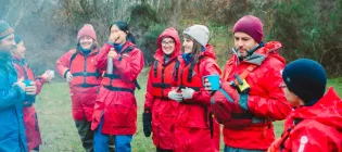 A group of students and staff, wearing red jackets, attending a nature-based learning course at Firbush, the University of Edinburgh's outdoor education centre in Perthshire.