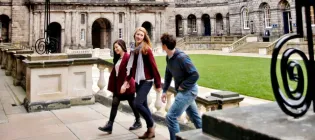 Three students walking up steps in Old College Quad, Edinburgh
