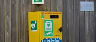 Defibrillator attached to the wooden wall in a park.