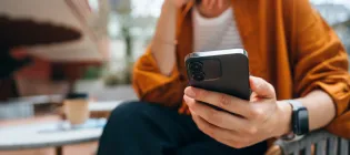 Close up shot of a person using a smartphone while sitting at a table