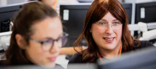 Two colleagues look happily at a computer screen