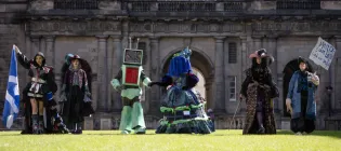 Six students pose on the lawn Old College Quad in costumes that will be on display during the 2025 Performance Costume Show