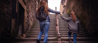 Mother holding a child's hands climbing a staircase