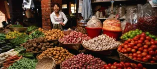 Woman smiling behind an abundance of colourful food at her market stall