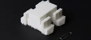 A four-legged robot made of soft plastic next to a paperclip