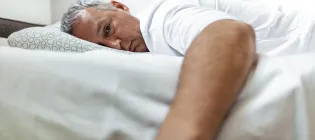 White male lying in a bed looking tired