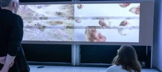 Two people lookng at a video screen of the Scottish landscape