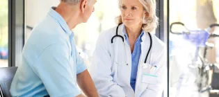 A female doctor talking to an elderly man