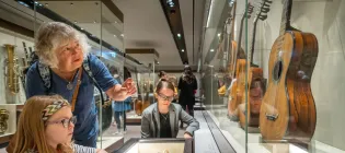 Two visitors examine an antique guitar at the ancient instrument museum at St Cecilia's Hall