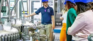 Group of people wearing hardhats being shown scientific equipmenttechnology