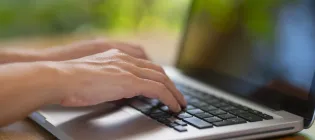 Blurred close-up image of person typing on a laptop
