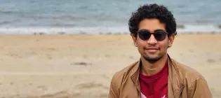 Sri looks at the camera. he is wearing sunglasses