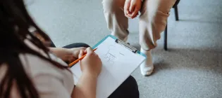Psychologist draws on a piece of paper while counseling a teenage girl