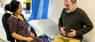 Male patient with stomach pain talking to female doctor