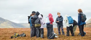 group of students standing in an open feild in windy conditions