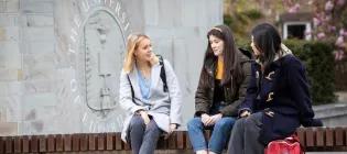 group of students sit on a bench at King's Buildings entrance