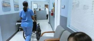 medical professional pushing wheelchair downb corrider