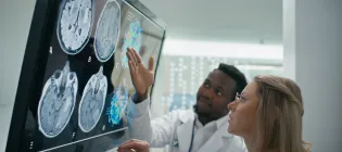 Two doctors look at images on a screen of brain scans