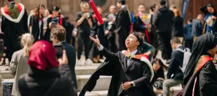 A student throwing his graduation scroll in the air outside McEwan Hall during the 2024 summer Graduations