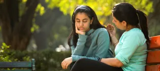 Mother comforting daughter at on park bench