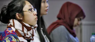 Three students sit in a seminar room