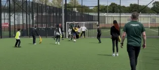 A group of young people playing football on an outside pitch at the University's Peffermill Playing Fields