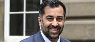 Head and shoulders photograph of Humza Housaf, stood in front of the Old Medical School, Edinburgh 