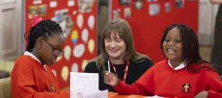Two School pupils sat at a classroom table with Kim Rowson, IntoUniversity Scotland Operations Manager 