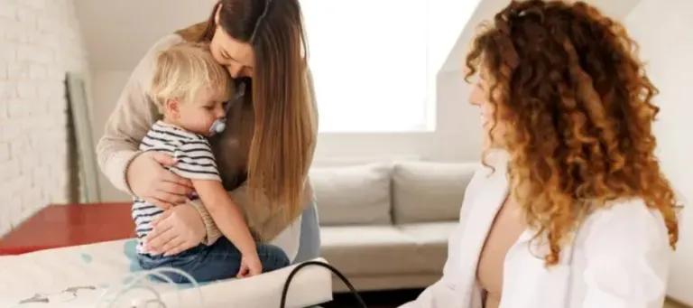 Mother holding child while being observed by doctor 