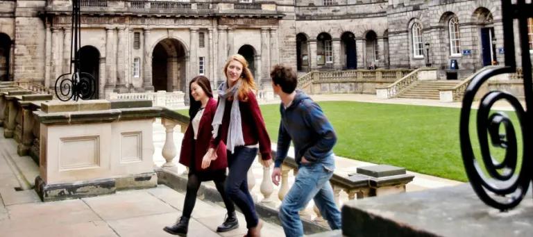 Three students walking through Old College Quad at the University of Edinburgh.