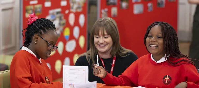 Two School pupils sat at a classroom table with Kim Rowson, IntoUniversity Scotland Operations Manager 