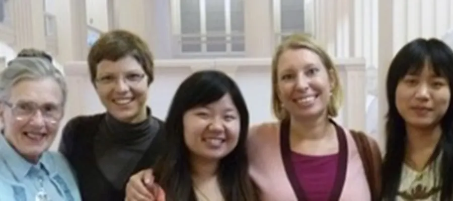 A group of women from the International Women's Club stand in a line smiling