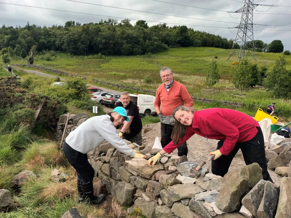 Four volunteers rebuild dry stone wall at Dumyat in Stirlingshire