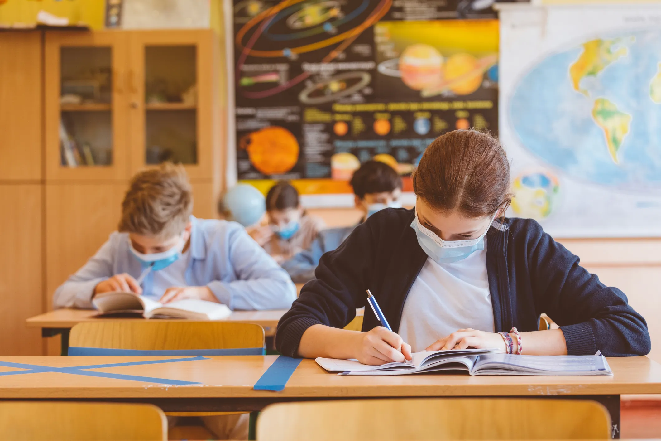 Children sitting at desks in a classroom with face coverings on