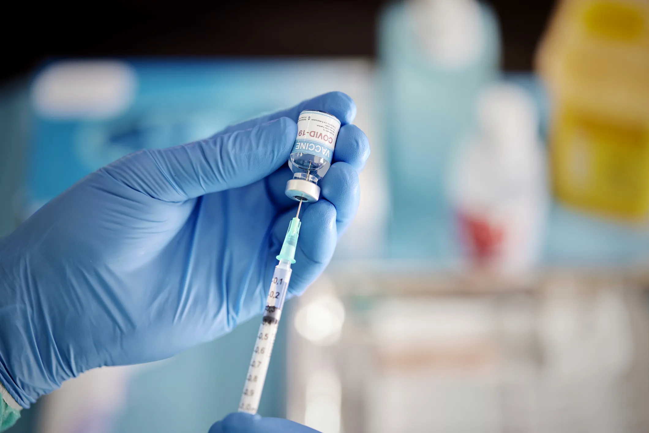 Photograph of the hands of a healthcare worker in rubber gloves preparing a covid vaccne