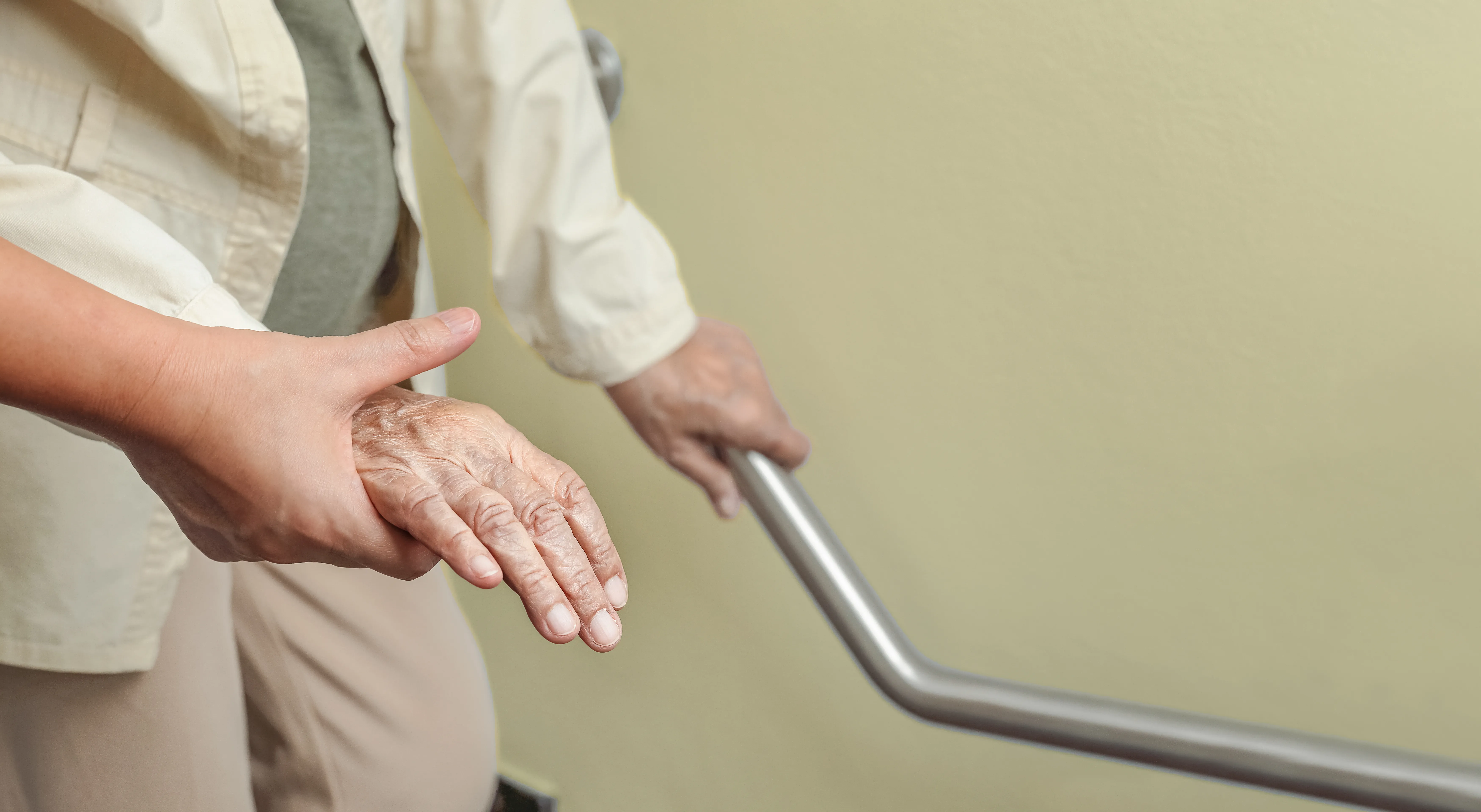 Elderly woman holding on handrail with caregiver 