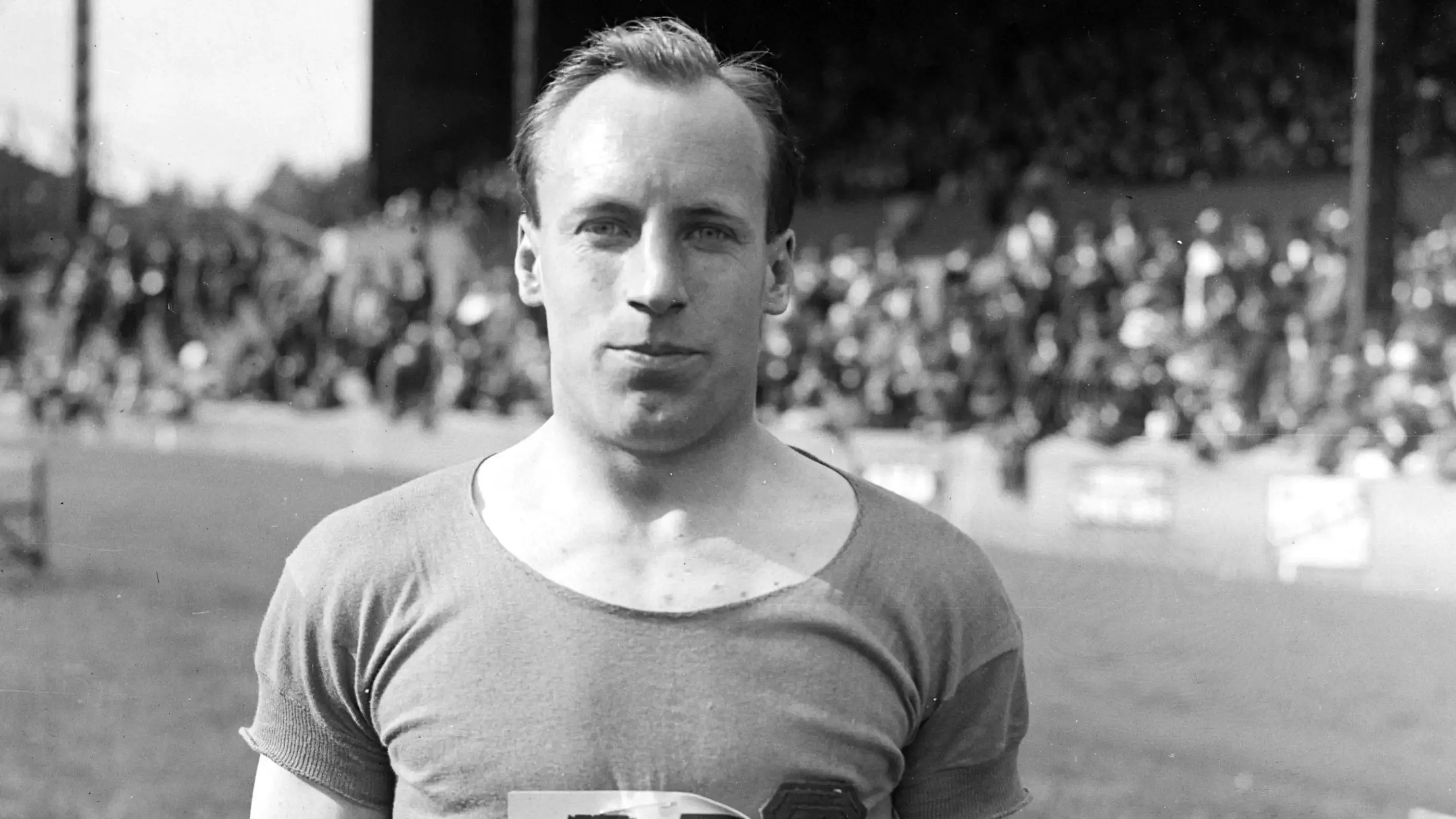 Athlete Eric Liddell stands on a sports field