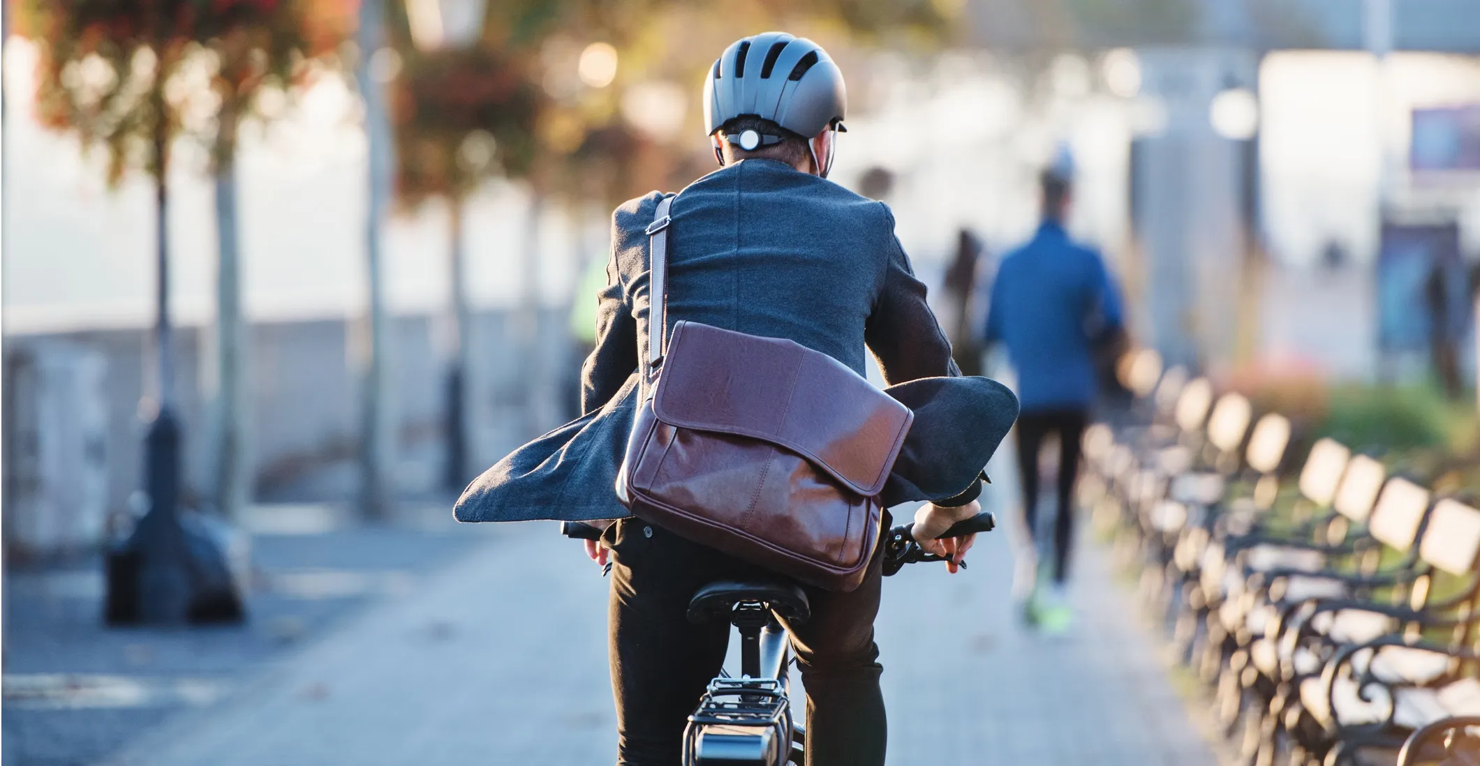 Rear view of a commuter on a bicycle traveling to work in a city.