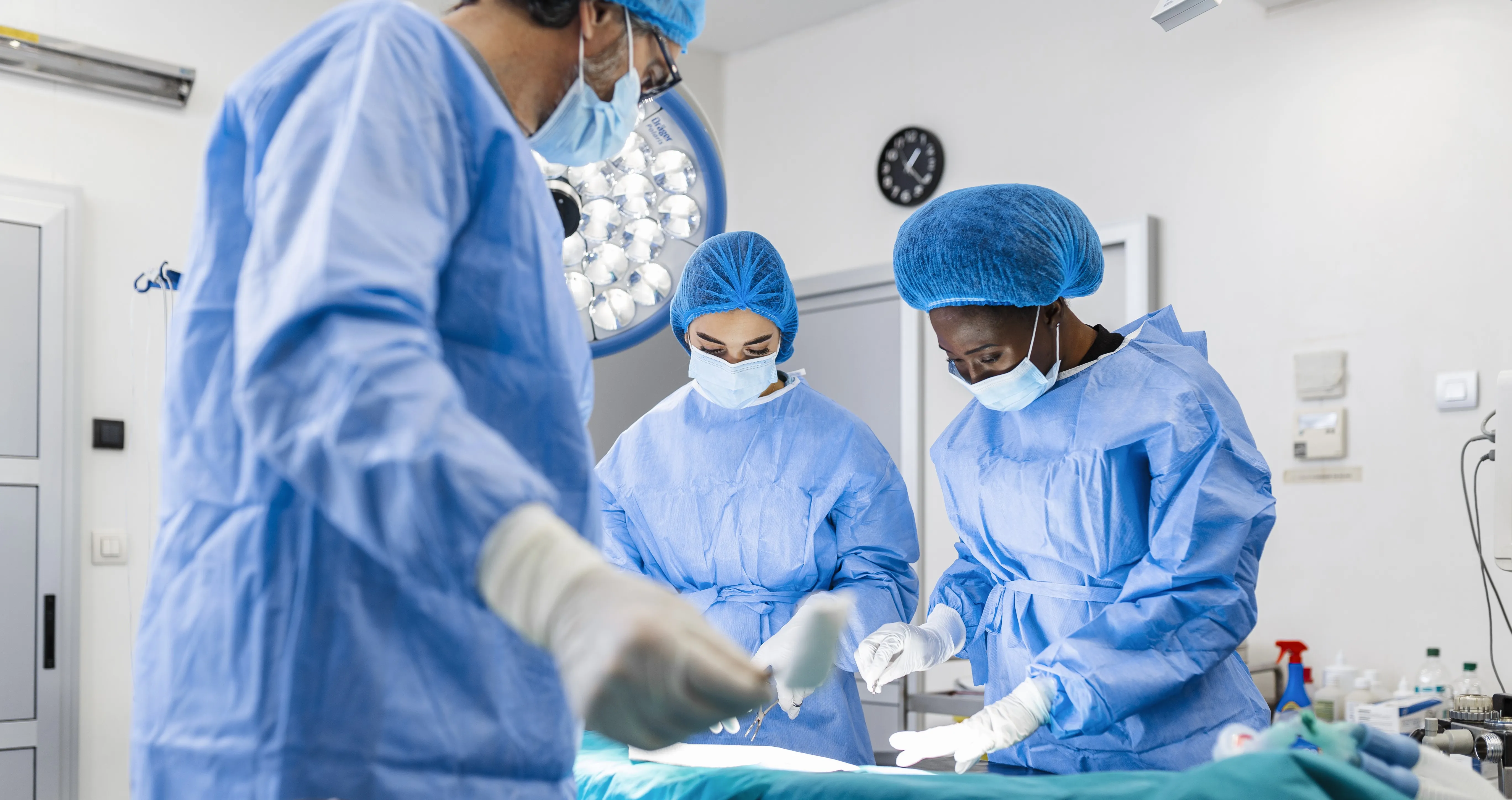 Three surgeons in operating theatre with table of instruments
