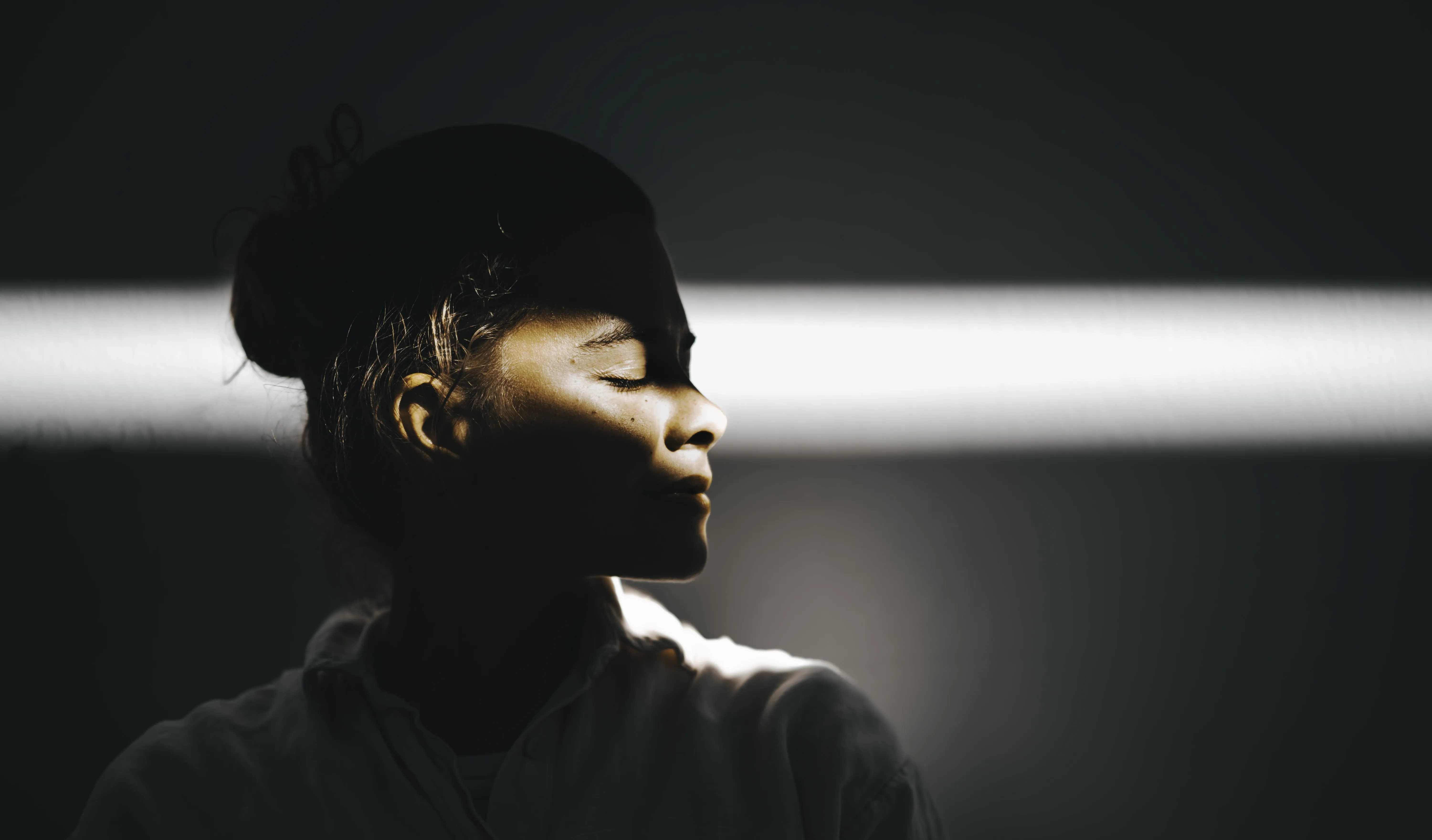 Portrait of woman with ray of sun across face