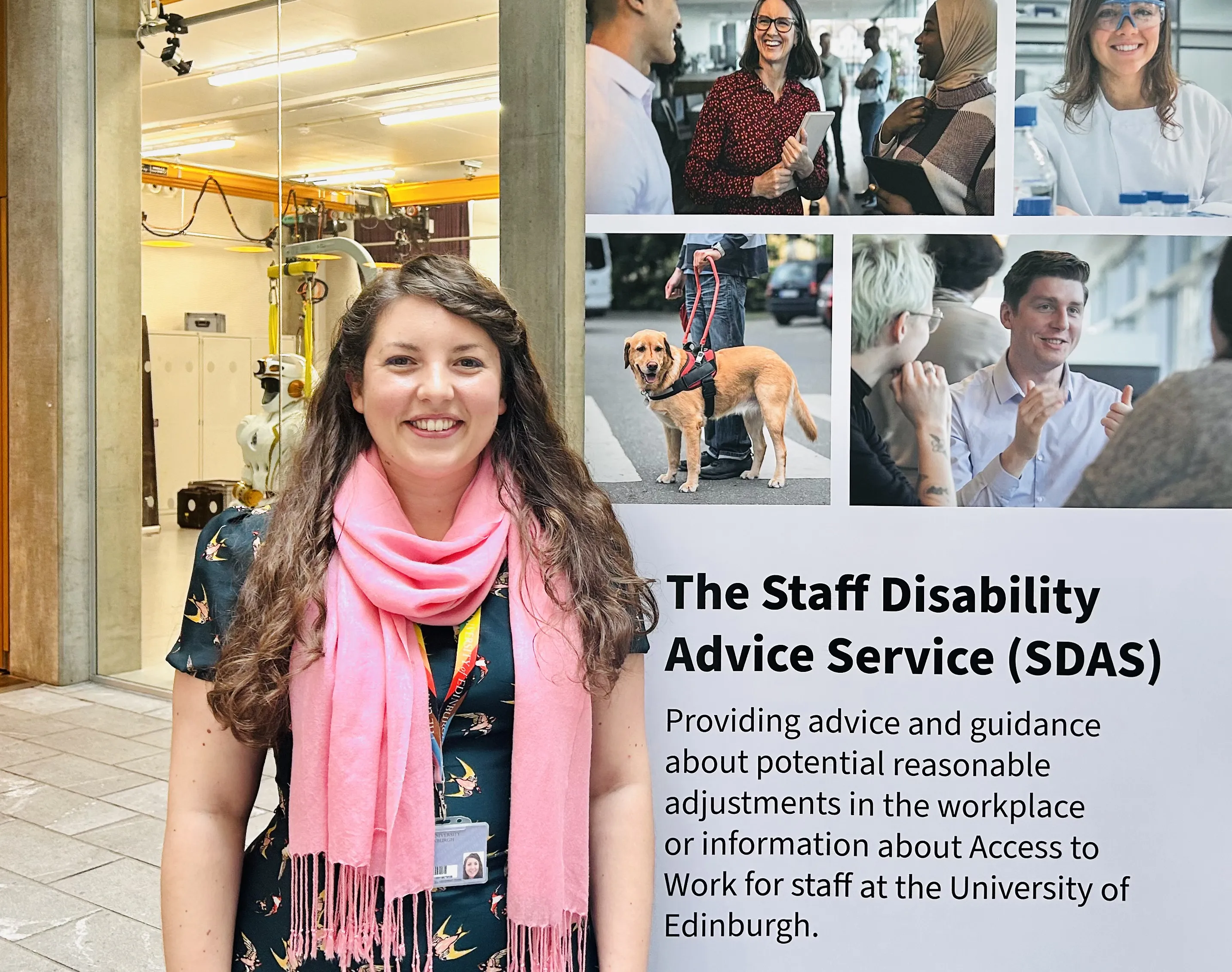 The Staff Disability Advisor stands in front of a promotional banner stand for the service at a launch event
